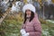 A girl in winter clothes on a walk in the park. He holds a snowball in his hands. Yellowed leaves are visible on the birch. The fi