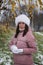 A girl in winter clothes on a walk in the park. He holds a snowball in his hands. Yellowed leaves are visible on the birch. The fi