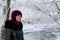 A girl in winter clothes Walking through the snow-covered park. Visible icebound river