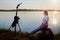 Girl or woman on the shore or beach of the lake in the evening at sunset and flash on the tripod stand. Photoshoot on nature near