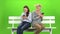 Girl and a woman are sitting on a bench and looking at the phones. Mobile dependency. Green screen