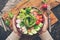 Girl in wool sweater holding a bowl of vegan salad with visible hands.Healthy vegan diet salad with fresh vegetables.View from