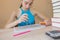 Girl is working with atlas at the wood table. Education and school concept - little student girl with many books