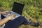 Girl working on a laptop on a haystack in countryside