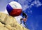 A girl wrapped in a flag of the United States of America raises a stone to the top in the form of a Czech flag silhouette