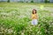 A girl with a wreath of daisies on her head and a net in her hands catches butterflies and has fun in a chamomile field in summer