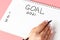 Girl writes in notepad of goal for 2021 on a pink background