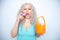 The girl yawns from boredom at Easter. the blonde is holding a basket with colored eggs and bored. white studio background.