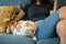 Girl and yellow color ragdoll cat resting on dark blue sofa