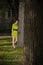 Girl in yellow dress leans on a tree in a park