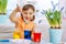 A girl in a yellow dress paints eggs for Easter in different colors. Table decoration and preparations for the holiday