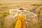 A girl in a yellow dress is playing in a wheat field and blowing soap bubbles. Nature in the village