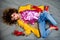 The girl in a yellow jacket and blue jeans with an afro hairdo lies on the floor. Fashion eighties, the era of disco.