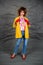 Girl in a yellow jacket and blue jeans with an afro hairstyle. Fashion of the eighties, disco era.