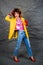 Girl in a yellow jacket and blue jeans with an afro hairstyle. Fashion of the eighties, disco era.