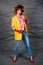 Girl in a yellow jacket and blue jeans with an afro hairstyle. Fashion of the eighties, disco era.