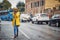 Girl in a yellow raincoat listens to music and walks in the rain