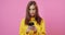 Girl in yellow raincoat using mobile over pink background
