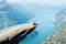 A girl in a yellow seats on the Trolltunga in Norway