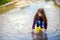 Girl in yellow sopog plays in a puddle in a small boat