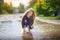 girl in yellow sopog plays in a puddle in a small boat