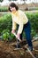 Girl in a yellow sweater digs beds with a shovel