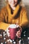 Girl in yellow sweater holding hot chocolate mug covered with marshmallow