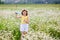 A girl in a yellow T-shirt and a wreath of daisies on her head plays in nature with soap bubbles. A child in a blooming chamomile