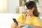 Girl in yellow using mobile phone on a sofa at home