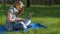 Girl in yoga pose with laptop. A teenage girl on nature is typing on a laptop. A teenager in a park wearing jeans and bracelets.