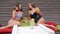 Girlfriends in bathing suits drink beverage sitting on colorful cushion, hen-party, girls in swimsuit with cocktails in