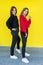 girlfriends posing together in modern knitted sweaters isolated on yellow wall studio portrait