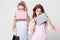 Girlfriends women in shirts with stylish handbags. Fashion spring image of two sisters. Pastel pink and blue colors