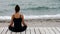 Girll sits in silence in lotus pose and meditating by the seaside