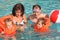 Girls bathing in lifejackets with parents in pool