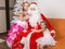 Girls in beautiful dresses hug Santa Claus sitting on a couch