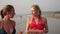 Girls in bikinis on the sea. Two young women girlfriends are walking along the beach