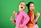 Girls with cheerful faces pose with candies on green background.