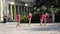 Girls from cheerleading team in pink tunics are dancing on playground.