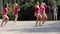 Girls from cheerleading team in pink tunics are dancing on playground.