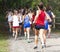 Girls cross country race on dirt path in woods taken from behind