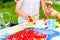 Girls cutting piece of strawberry cake in garden