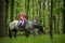 Girls enjoying horseback riding in the woods with mother, young pretty girls with blond curly hair on a horse, freedom