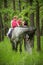 Girls enjoying horseback riding in the woods with mother, young pretty girls with blond curly hair on a horse, freedom