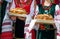 Girls in ethnic Bulgarian clothes holding traditional beautiful loaf