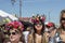 Girls at festival wearing flower crowns with streamers walking in street among crowd - close-up and selective