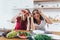 Girls fooling around in the kitchen playing with vegetables.