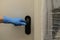 A girls hand in a blue protective glove holds a black doorknob to open or close the door. Antibacterial prophylaxis in times of