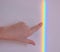 A girls hand pointing a rainbow line on the wall