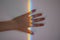 A girls hand under a rainbow colored line